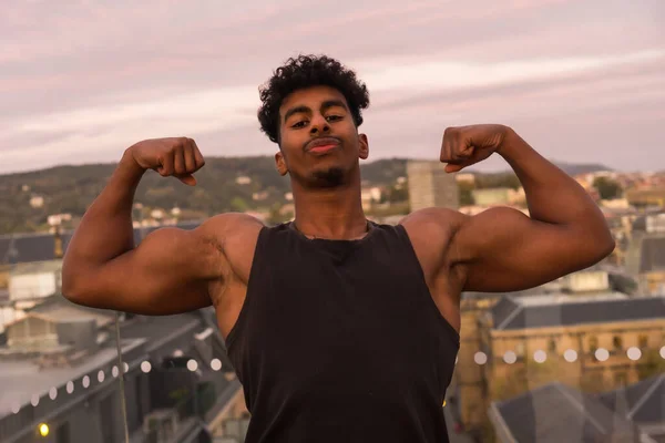 Arab young bodybuilder doing sports in the city, showing off his big arm muscle