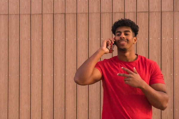Arab Mladý Muž Červeném Tričku Dřevěném Pozadí Úsměvem Mluví Telefonu — Stock fotografie