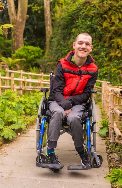 도시의 공원에서 조끼를 마비된 청년의 모습이었습니다 휠체어에 앉아서 웃으면서 — 스톡 사진