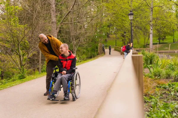 Förlamad Ung Man Rullstol Som Knuffas Vän Offentlig Stadspark Strosar — Stockfoto