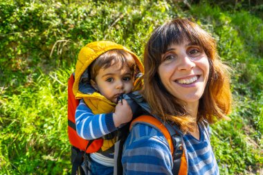 Sırt çantalı genç bir annenin portresi Cangas de Onis yakınlarındaki Tornin la la Olla de San Vicente arasında Sella nehrine bakıyor. Asturyalar. İspanya