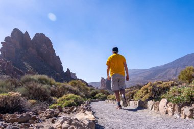 Tenerife, Kanarya Adaları 'ndaki Teide' nin doğal bölgesinde Roques de Gracia ve Roque Cinchado arasında yürüyen bir turist.