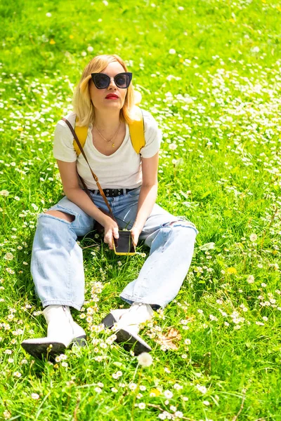 Portret Blondynki Turystki Kapeluszu Okularach Przeciwsłonecznych Siedzącej Wiosną Trawie Obok — Zdjęcie stockowe