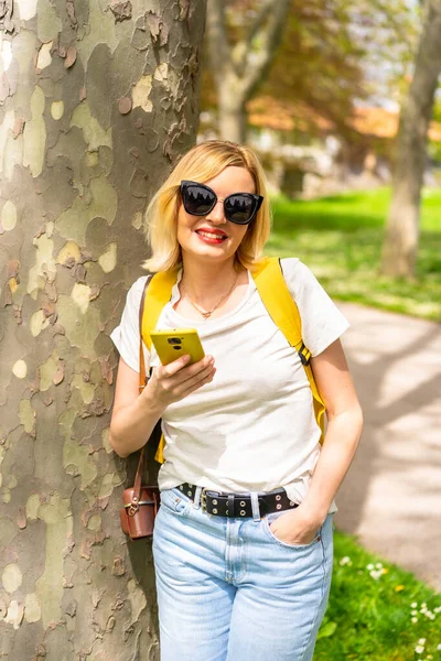 Portret Blondynki Turystki Kapeluszu Okularach Przeciwsłonecznych Opierającej Się Drzewie Wiosną — Zdjęcie stockowe