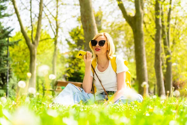 Turystyczna Blondynka Wysyłająca Wiadomość Głosową Telefonem Kapeluszu Okularach Przeciwsłonecznych Siedząca — Zdjęcie stockowe