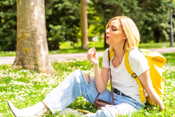 Blondynka Dmuchająca Kwiatka Mniszka Lekarskiego Parku Mieście Kapeluszu Okularach Przeciwsłonecznych — Zdjęcie stockowe