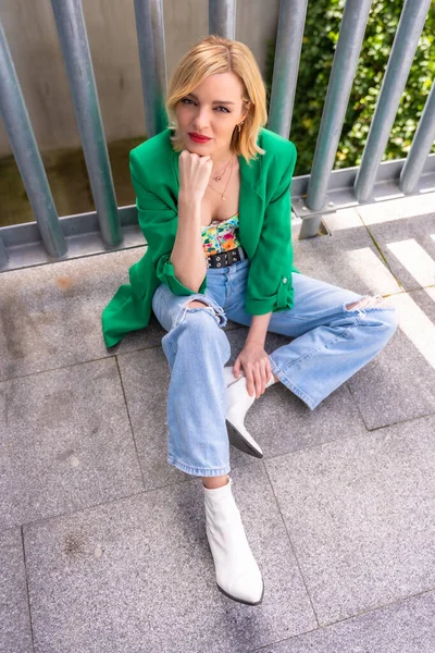 Uma Mulher Modelo Loira Com Uma Jaqueta Verde Sentada Chão — Fotografia de Stock