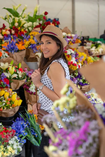 Şapkalı güzel bir turist çiçek pazarına gider, bahar veya yaz tatilinin tadını çıkarır.