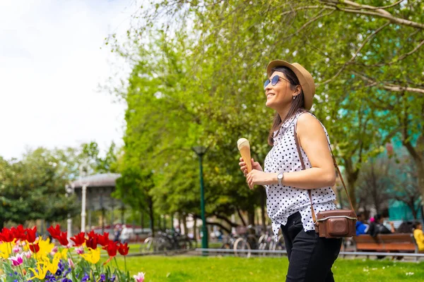 アイスコーンを食べながら街を歩く観光客の女性 夏休みを楽しむカメラ付きのソロ女性旅行者のコンセプト — ストック写真