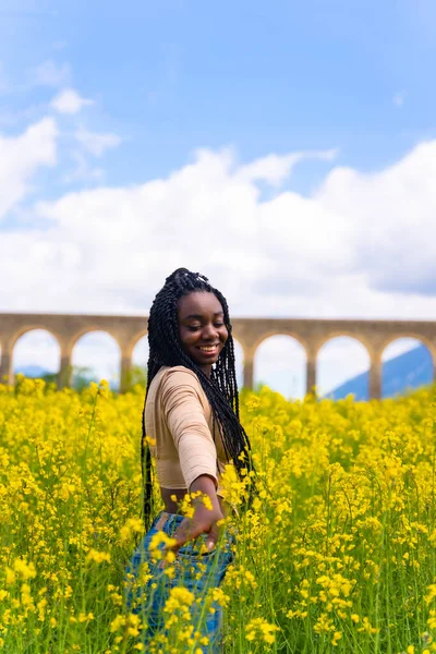 Yaşam tarzı, doğanın keyfi, sarı çiçekli bir tarlada örgülü, gezgin siyah etnik bir kızın portresi.
