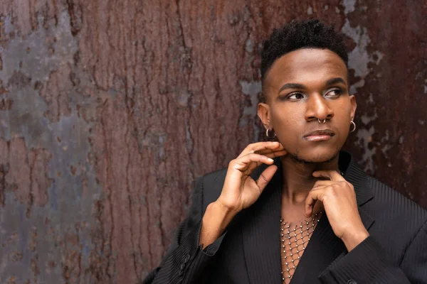 Siyahi bir etnik adam kahverengi metalik arka planda poz veriyor.