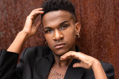 Siyah etnik kökenli bir adamın portresi kahverengi metalik arka planda poz veriyor.