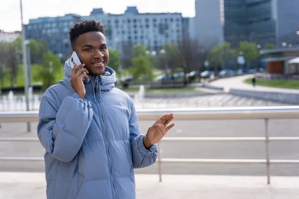 Černý Etnický Muž Telefonem Modrou Bundou Městě Mluví Telefonu — Stock fotografie