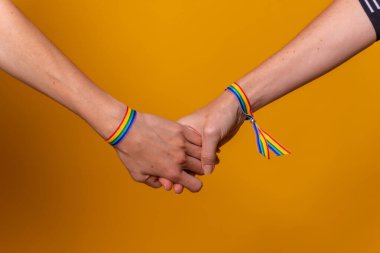 İki kadının elleri, sarı arka planda LGBT konsepti, lezbiyen kız çift