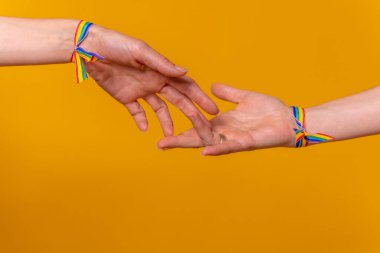 El ele tutuşan iki kadının elleri, sarı arka planda LGBT konsepti, birkaç lezbiyen kız.