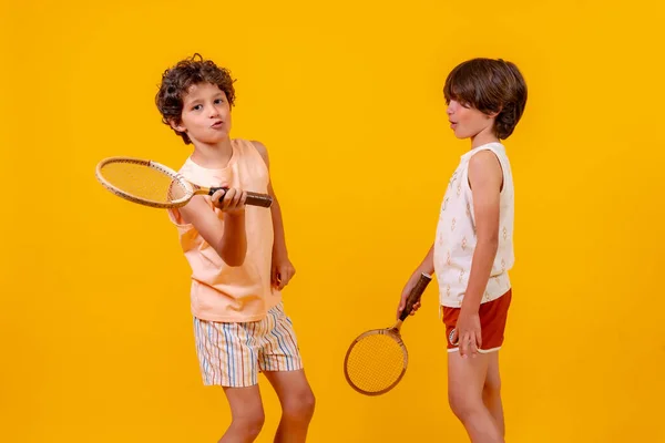 Dos Niños Jugando Tenis Divirtiéndose Verano Fondo Amarillo —  Fotos de Stock