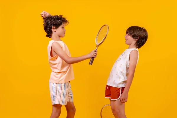 Двоє Дітей Грають Теніс Розважаються Жовтий Фон — стокове фото