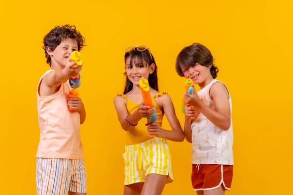 Niños Divirtiéndose Con Pistolas Agua Vacaciones Verano Fondo Amarillo —  Fotos de Stock