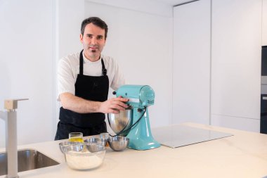 Erkek bir fırıncı evde kırmızı kadife kek pişiriyor, pastayı makinede hazırlıyor, evde çalışıyor.