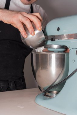 Evde kırmızı kadife kek pişiren, sirke ve kabartma tozuyla karıştıran, yemek işlemcisine ekleyen, evde çalışan bir adamın elleri.