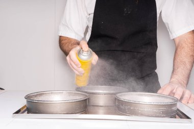 Evde kırmızı kadife kek pişiren, küflere tereyağı sıkan, evde çalışan bir adamın elleri.