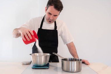 Meydan okuyan adam evde kırmızı kadife kek pişiriyor, İsviçre kremasını yumurta beyazıyla hazırlıyor, şeker ekliyor, evde çalışıyor.