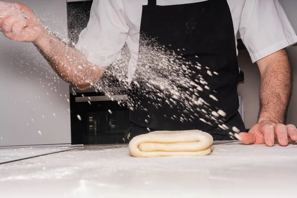 Confectioner man cooking homemade croissants, preparing the puff pastry and adding flour, work at home