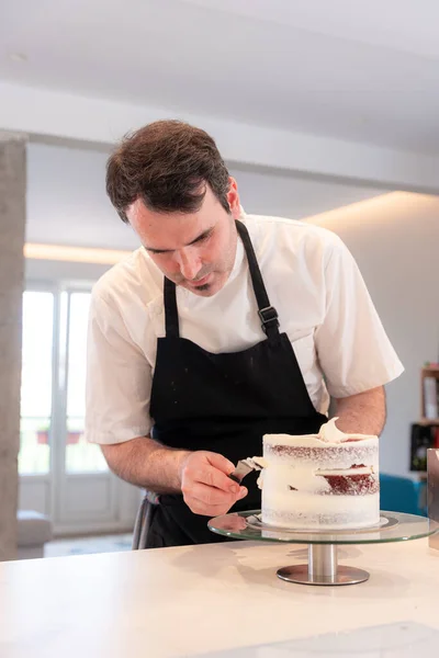 A challenger man cooking a red velvet cake at home, with the smoothing spatula leaving the perfect circle