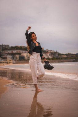 Yazın sahilde dans eden ve eğlenen sarışın bir kadının portresi.