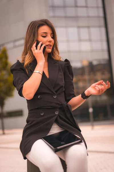 Blonde entrepreneur woman outside the office talking on the phone a work call