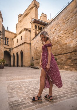 Ortaçağ şatosunda kırmızı elbiseli sarışın bir kadının portresi.