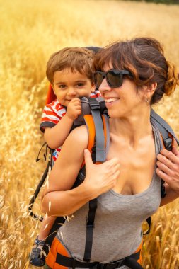 A woman with her son in a field of yellow wheat grain ready for harvest, summer vacation