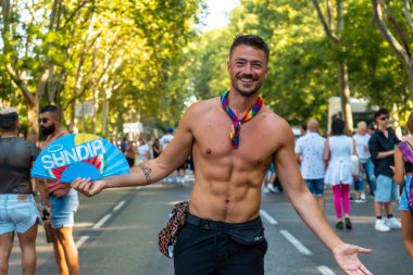 Madrid, Spain: July 9, 2022: A young man having fun at the gay pride party, lgbt in Madrid, rainbow flag and fan