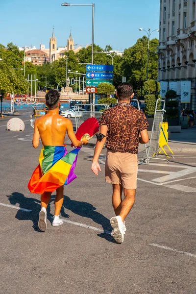 Madrid, Spain: July 9, 2022: Two young men heading to the parade at the gay pride party, lgtb in Madrid with the rainbow flag