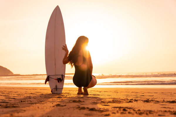 Beautiful surfer woman on the beach at sunset. Bali Indonesia.