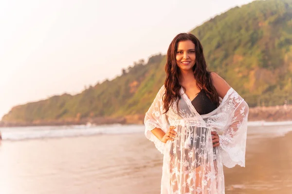 Portrait of a woman at sunset in a white dress enjoying the summer at the beach
