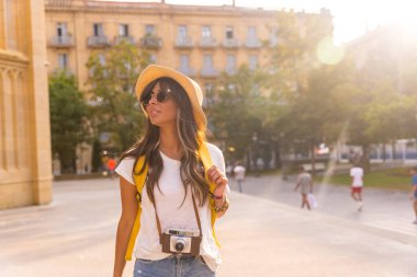 Yaz günbatımında şapkalı bir turist elinde fotoğraf makinesi olan bir kilisenin yanında.
