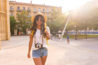 Yaz günbatımında şapkalı bir turist elinde fotoğraf makinesi olan bir kilisenin yanında.