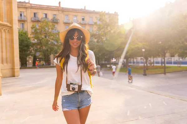 Yaz günbatımında şapkalı bir turist elinde fotoğraf makinesi olan bir kilisenin yanında.