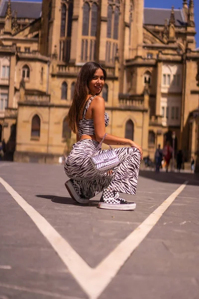 Young Brunette Squatting City Church Summer Zebra Print Jumpsuit — стоковое фото