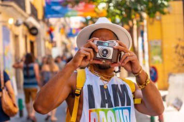 A gay black man at the pride party taking photos, LGBT flag