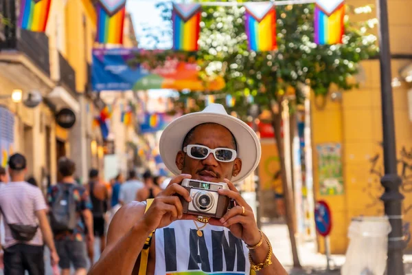 A gay black man at the pride party taking photos, LGBT flag
