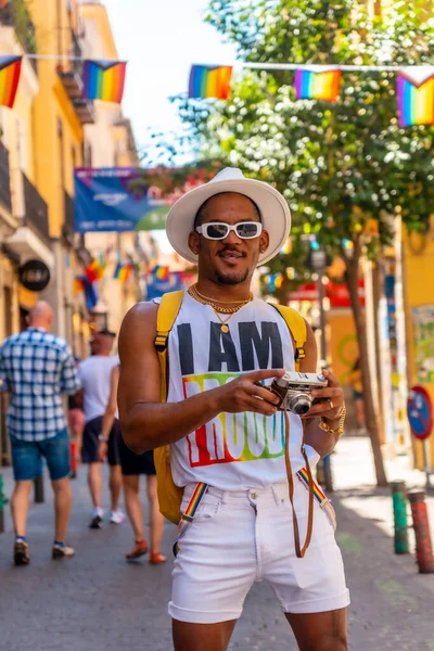 A gay black man at the pride party looking at the photos on the camera, LGBT flag