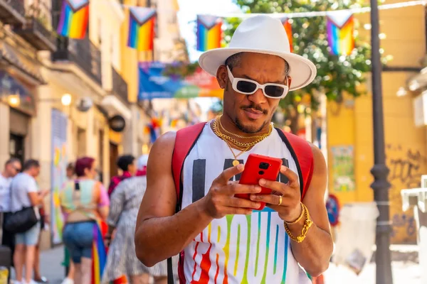 A gay black man at the pride party writing a message with the phone, LGBT flag