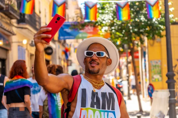 A gay black man at the pride party taking a selfie with the phone, LGBT flag