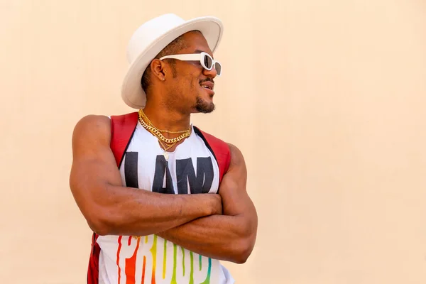 Black gay man at pride party on cream wall, LGBT flag, facing right