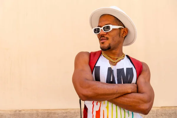 Black gay man at pride party on cream wall, LGBT flag, facing left