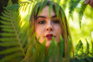 Portrait of a young woman in nature in a natural park with some fern leaves