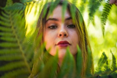 Portrait of a young woman in nature in a natural park with some fern leaves