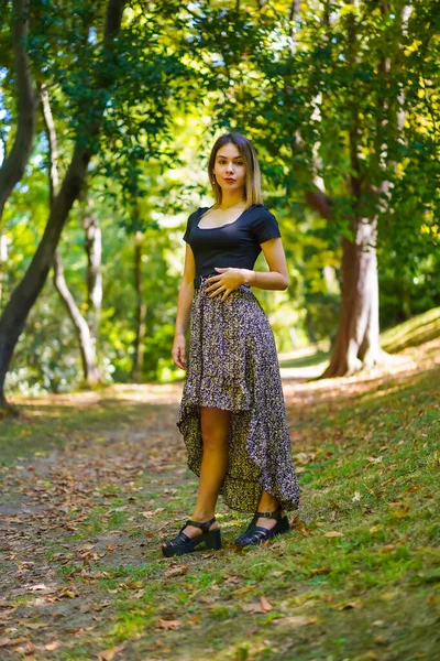 Posing of a young brunette woman in nature walking through the natural park in autumn